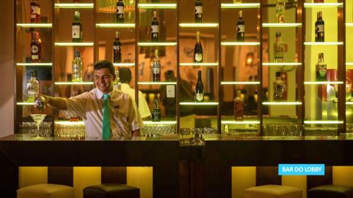 a man is standing behind a bar with glasses at Vila Galé Resort Touros - All Inclusive in Touros