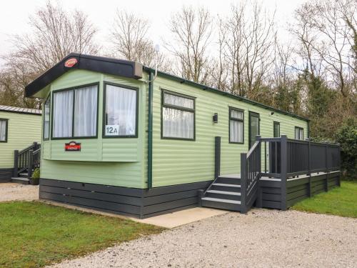 a green tiny house with a staircase in a yard at 12A Borwick Lakes in Carnforth