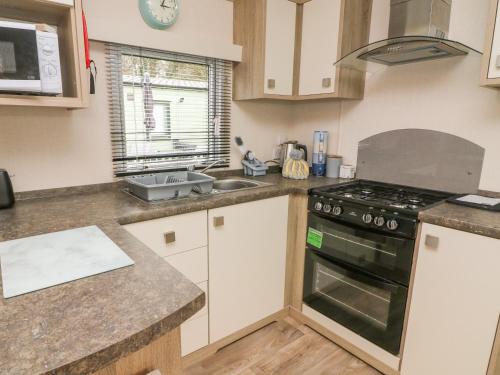 a kitchen with a stove top oven next to a sink at 12A Borwick Lakes in Carnforth