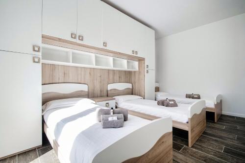 two beds in a room with white walls and wooden floors at Silvia Lenno House - The House Of Travelers in Lenno
