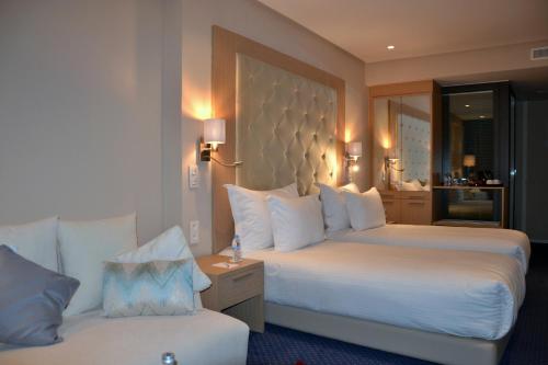 a hotel room with two beds and a couch at Flower Town Hotel & Spa in Rabat