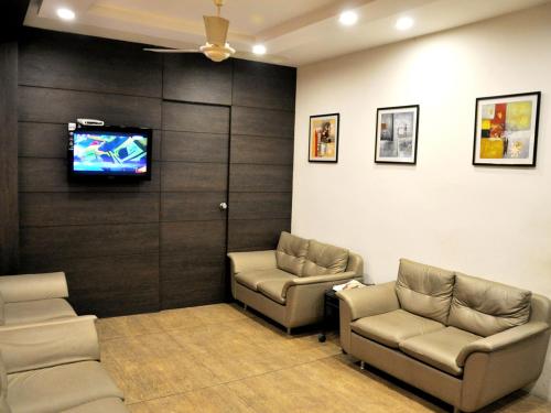 a waiting room with two couches and a flat screen tv at Hotel Jyoti in Rajkot