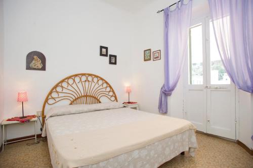 Schlafzimmer mit einem Bett mit lila Vorhängen und einem Fenster in der Unterkunft Isola Blu in Marina di Campo