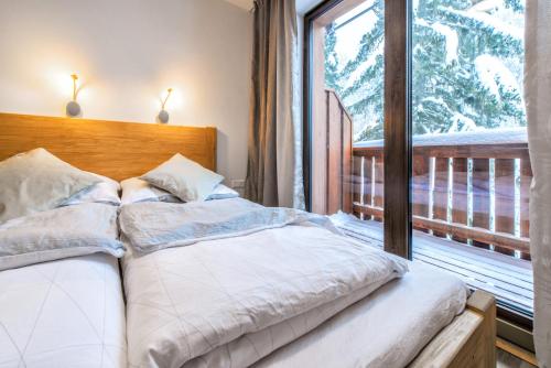 a bedroom with a bed and a large window at Apartments Srdiecko - JASNA South, FOREST View, SAUNA in One Apt FIREPLACE in Both in Tale