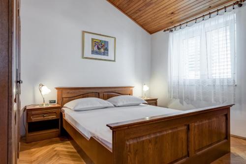 a bedroom with a wooden bed and a window at Beachfront Apartment Pisak (196-2) in Pisak