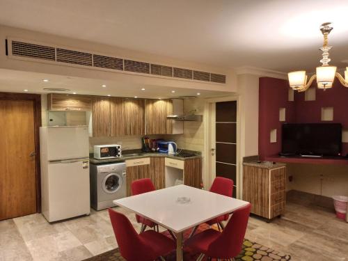 una cucina con tavolo bianco e sedie rosse di Monte Cairo Serviced Apartments a Il Cairo