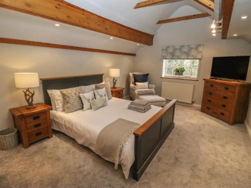 a bedroom with a large bed and a television at The Coach House Apartment in Tewkesbury