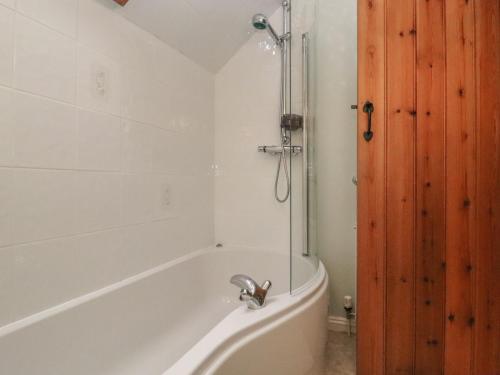 y baño con bañera blanca y ducha. en The Coach House Apartment, en Tewkesbury