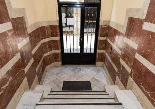 un corridoio con porta nera e scale in un edificio di Pension Salamanca a Salamanca