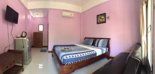 a bedroom with a bed in a room with pink walls at MossMan House in Ko Samed