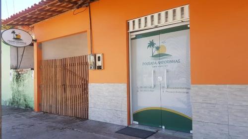 ein orangefarbenes Gebäude mit einer Tür mit einem Schild drauf in der Unterkunft Pousada Andorinhas in Santo Amaro