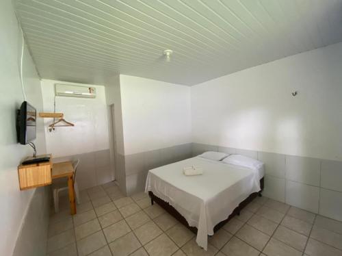 a bedroom with a white bed and a table at Pousada Andorinhas in Santo Amaro