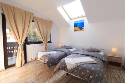 two twin beds in a room with a window at Stars & Mountain Apartment in Buşteni
