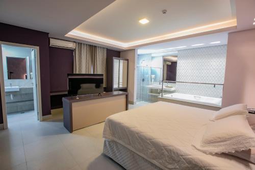 a bedroom with a bed and a tub and a television at Grand Carimã Resort & Convention Center in Foz do Iguaçu