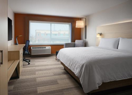 a hotel room with a bed and a desk and a window at Holiday Inn Express & Suites - Lockport by IHG in Lockport