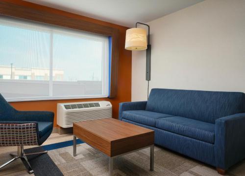 a living room with a blue couch and a table at Holiday Inn Express & Suites - Lockport by IHG in Lockport