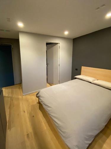 a bedroom with a large white bed and wooden floors at Empire - Affittacamere in Modena