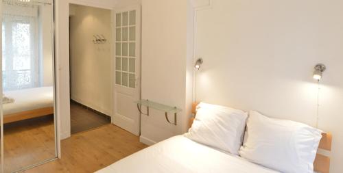 1 dormitorio con cama blanca y espejo en Appart' Ney en Lyon