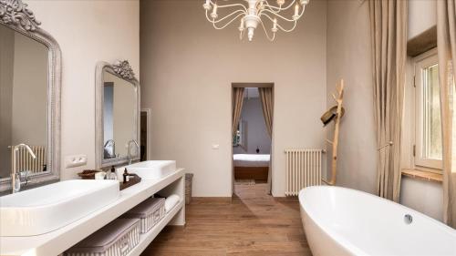a bathroom with two sinks and a tub and a chandelier at Cinque Cipressi 8, Emma Villas in Montecatini Val di Cecina