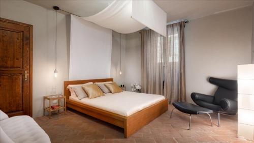 a bedroom with a bed and a chair at Cinque Cipressi 8, Emma Villas in Montecatini Val di Cecina