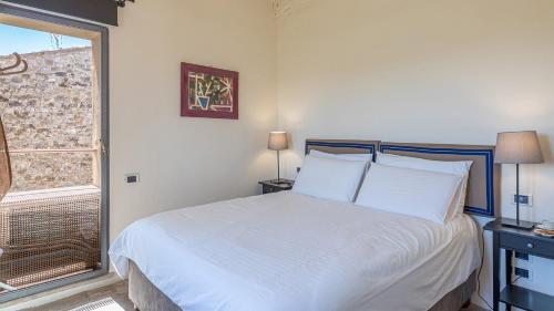 a bedroom with a bed with white sheets and a window at CONTESSA MATILDE 16, Emma Villas in Collazzone