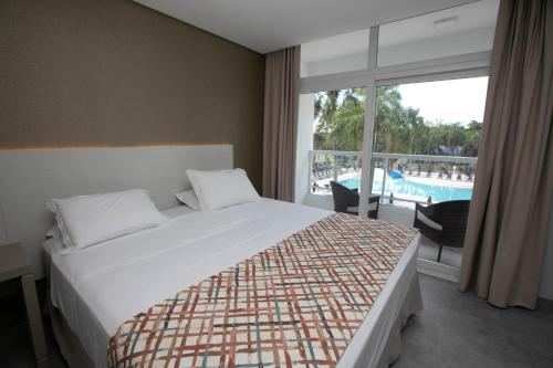 a bedroom with a bed and a balcony with a pool at Grand Carimã Resort & Convention Center in Foz do Iguaçu