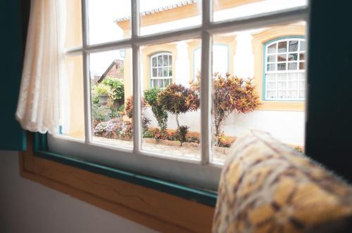 a window with a view of a house with flowers at Pousada Richard Rothe in Tiradentes