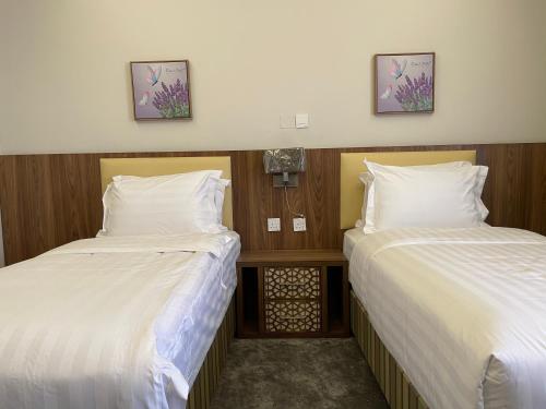 two beds sitting next to each other in a room at فندق حديقة القصور in Şāmitah