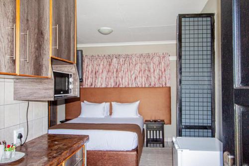 ein Hotelzimmer mit einem Bett und einem TV in der Unterkunft PW Heights Private Guest House in Thohoyandou