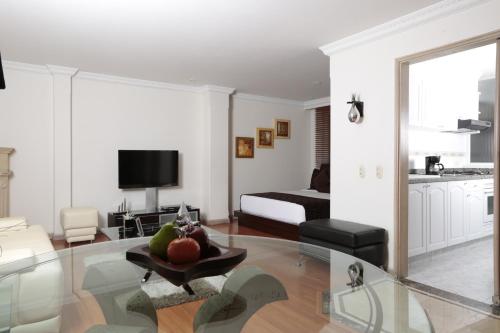 a living room with a table and a room with a bed at Hotel Suites 108 in Bogotá