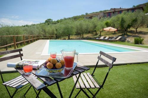 a table with a bowl of fruit and drinks on it next to a pool at Villa La Poiana 10 Emma Villas in Radda in Chianti