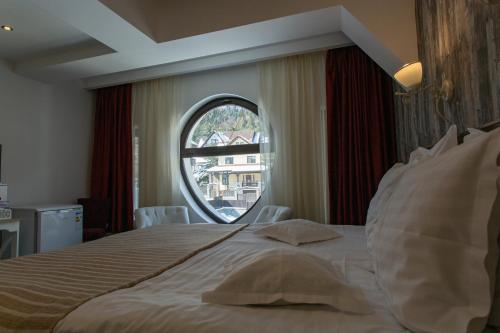 a bedroom with a large bed with a round window at Pensiunea Carmen`s Mansion B in Sinaia