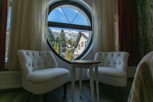 a room with two chairs and a round window at Pensiunea Carmen`s Mansion B in Sinaia
