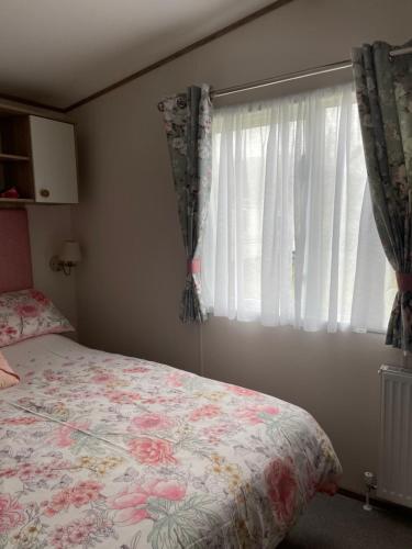 a bedroom with a bed and a window with curtains at The Wimbledon 70 in Dunoon