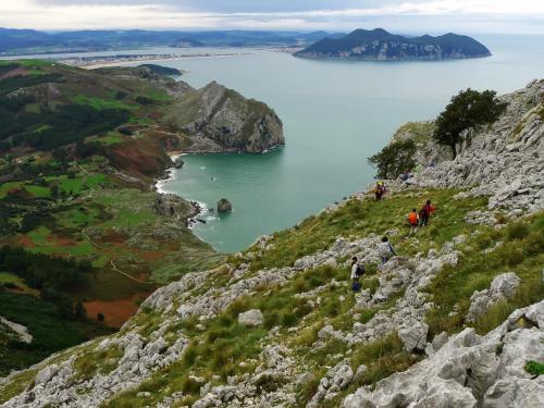 a group of people walking on a mountain overlooking a body of water at Posada y Apartamentos Trebuesto de Guriezo in Trebuesto