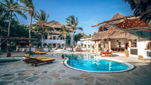 a pool at a resort with chairs and palm trees at Temple Point Resort in Watamu