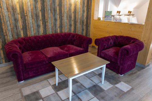 a living room with two purple couches and a table at Pensiunea Carmen`s Mansion B in Sinaia