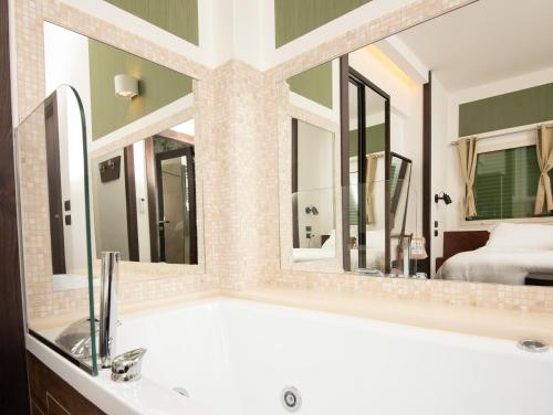 a bathroom with a tub and two mirrors at Domus Vista Castello in Naples