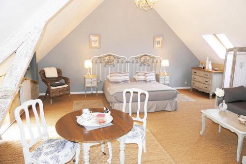 una camera da letto con un letto, un tavolo e delle sedie di Les Pérelles a Saint-Vigor-le-Grand
