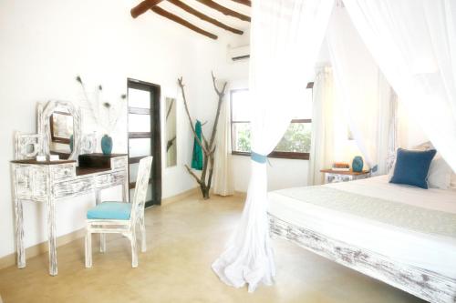 a white bedroom with a bed and a chair at Temple Point Resort in Watamu