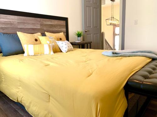 a large yellow bed with pillows on top of it at The Iron Scow - With Private Yard & Free Parking, Minutes From Falls & Casino by Niagara Hospitality in Niagara Falls