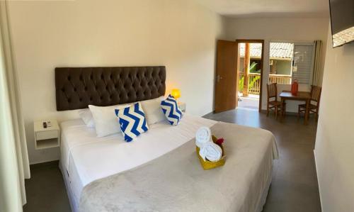 a bedroom with a large white bed with blue and white pillows at TBS Prime Suítes in São Sebastião