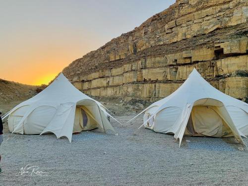 dos tiendas de campaña en la playa al lado de un acantilado en Selina Ramon en Mitzpe Ramon