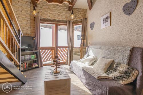 a living room with a couch and a tv at Résidence Les hauts de Val Cenis in Lanslevillard