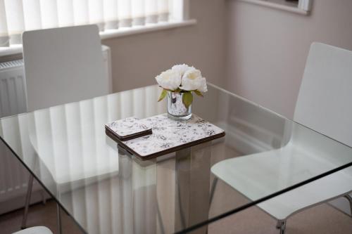 a glass table with a vase of flowers on it at Alexandra Lodge Stylish Ground-Floor Flat in Swansea