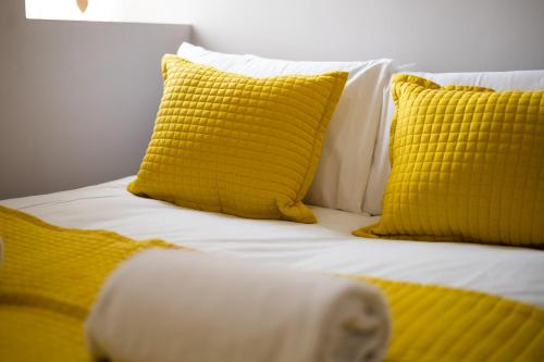 a bed with yellow and white pillows on it at Alexandra Lodge in Swansea