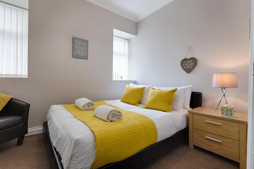 a bedroom with a bed with a yellow blanket at Alexandra Lodge Stylish Ground-Floor Flat in Swansea
