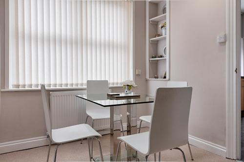 a dining room with a table and white chairs at Alexandra Lodge Stylish Ground-Floor Flat in Swansea