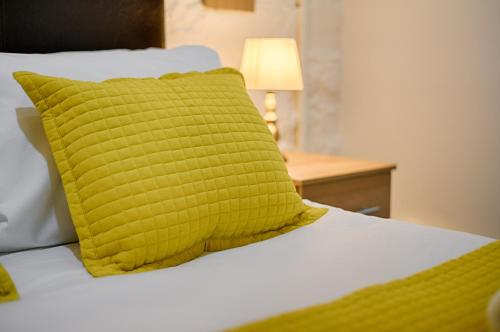 a bed with a yellow pillow and a lamp on a table at Alexandra Cottage Comfortable Apt near Swansea & M4 in Swansea