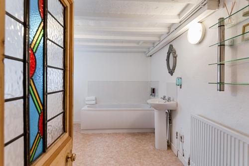baño con bañera, lavabo y ventana en Alexandra Cottage, en Swansea